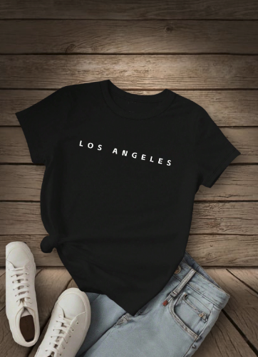 Black t-shirt with 'LOS ANGELES' text on a wooden surface with white sneakers and light blue jeans.