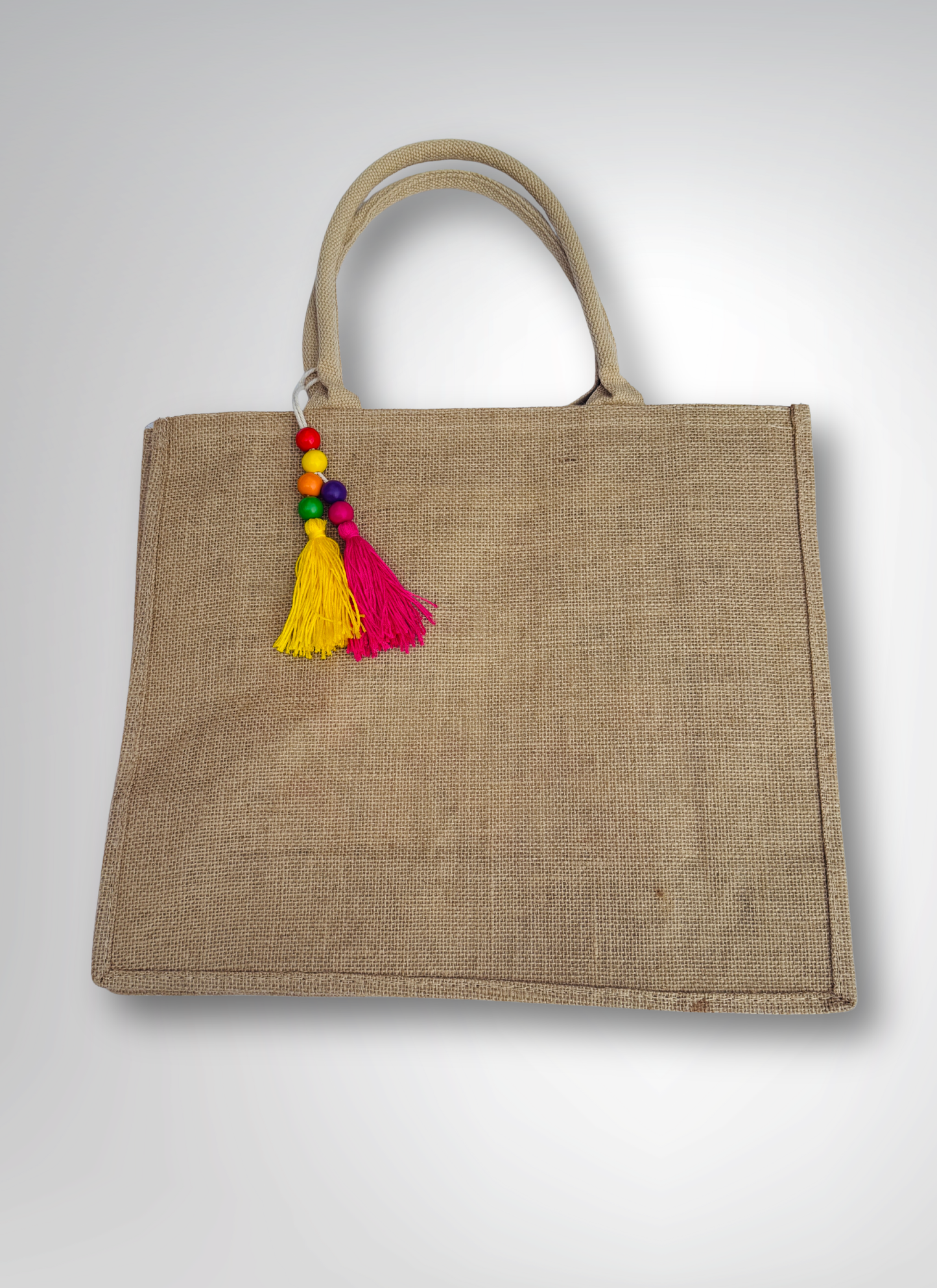 Jute bag with colorful tassel on a light gray background